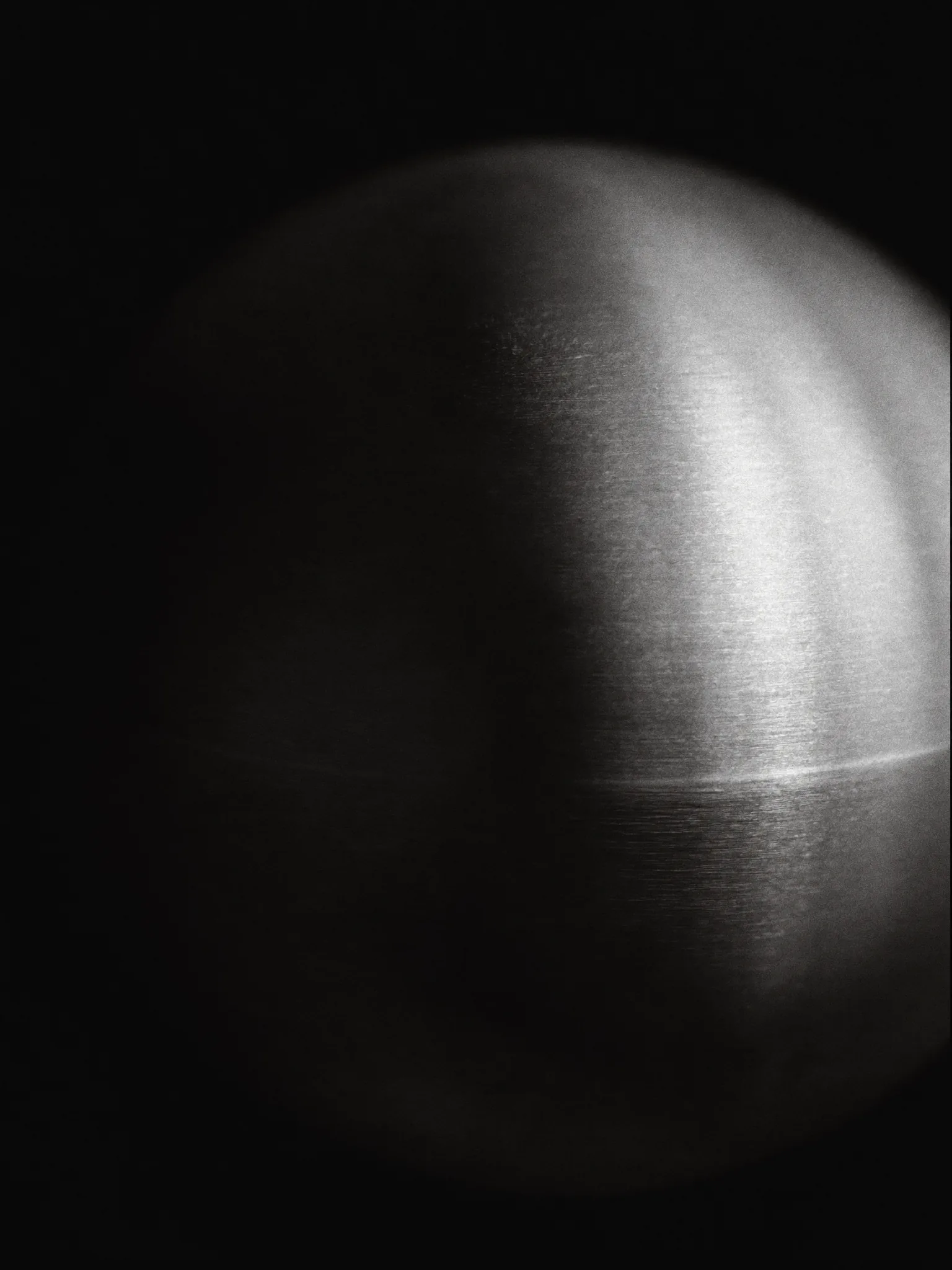 Esfera de acero cepillado en penumbra, luz rasante