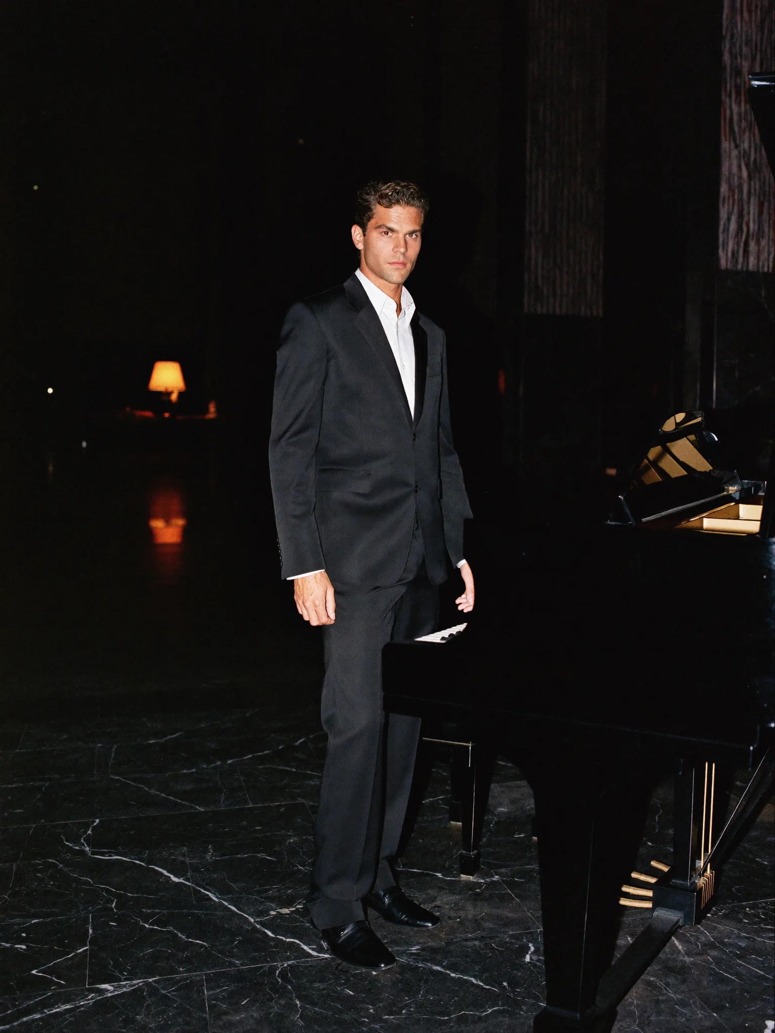 Retrato masculino de noche junto a un piano de cola