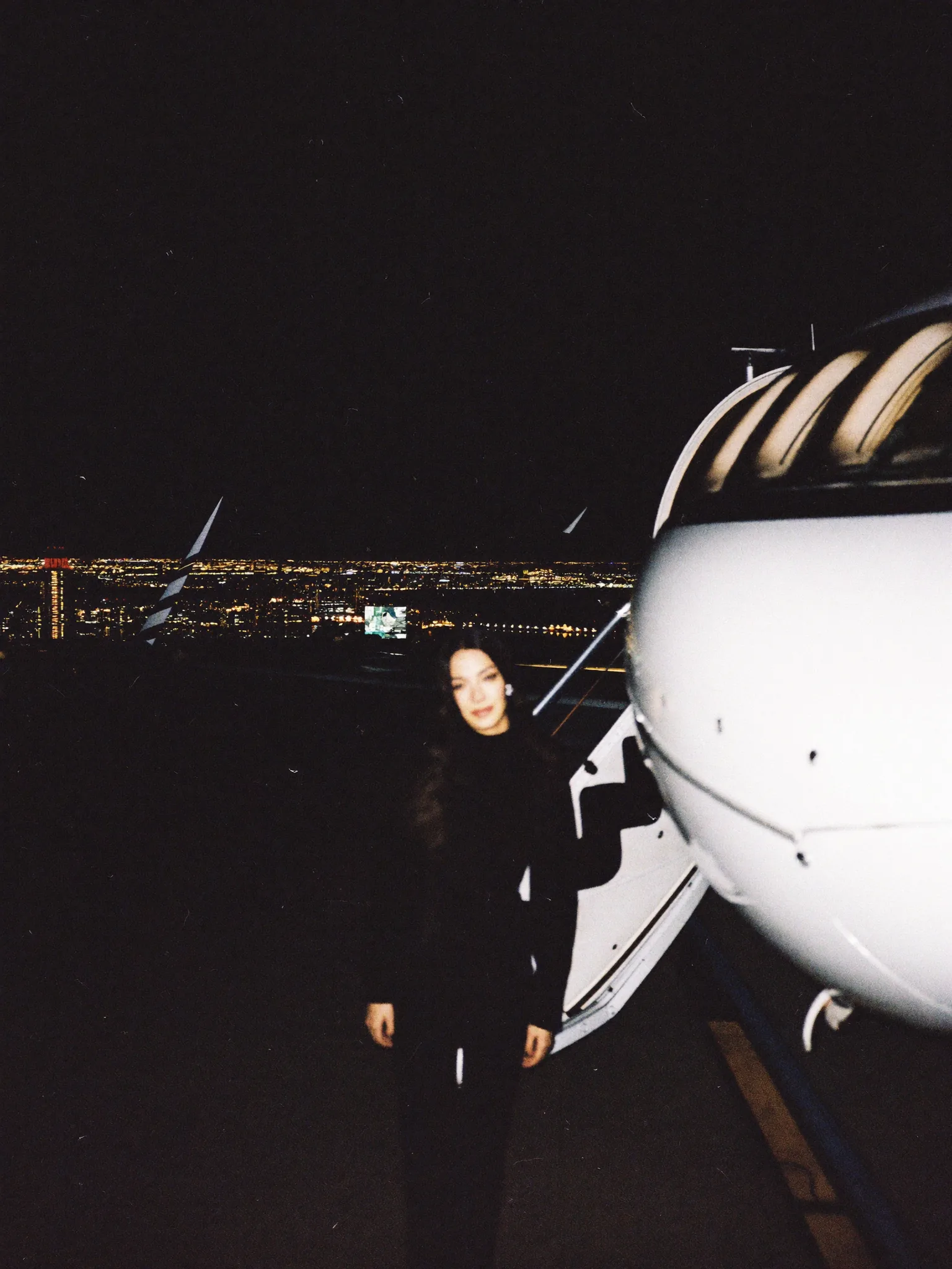 Figura junto a un jet privado con la ciudad iluminada detrás